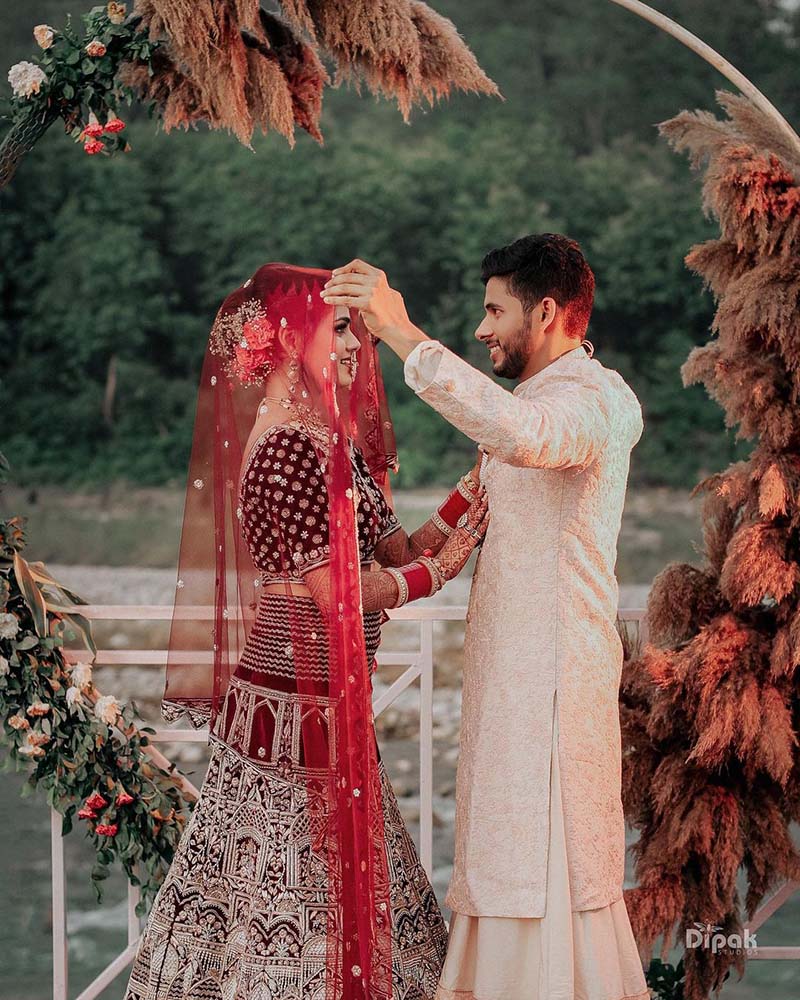 Photo of Bride in red sabya lehenga and groom in ivory sherwani